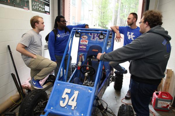Several students standing around a race car